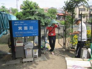 箕面川と書かれた看板の横に立つ2人の方の写真